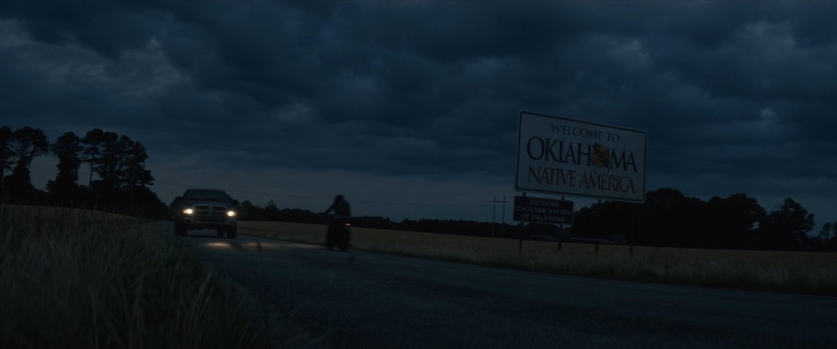 Motorcycle on country road at night. Sign: Welcome to Oklahoma Native America.