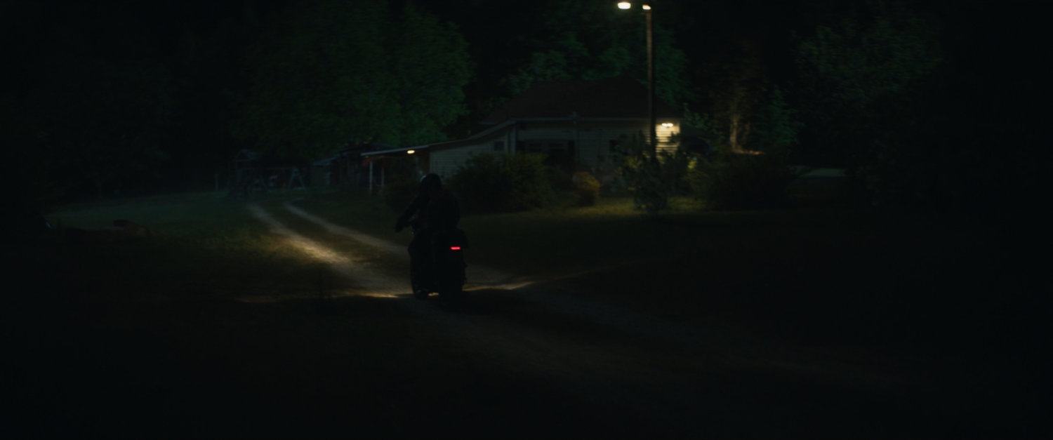 Motorcycle pulls up to Lopez house at night.