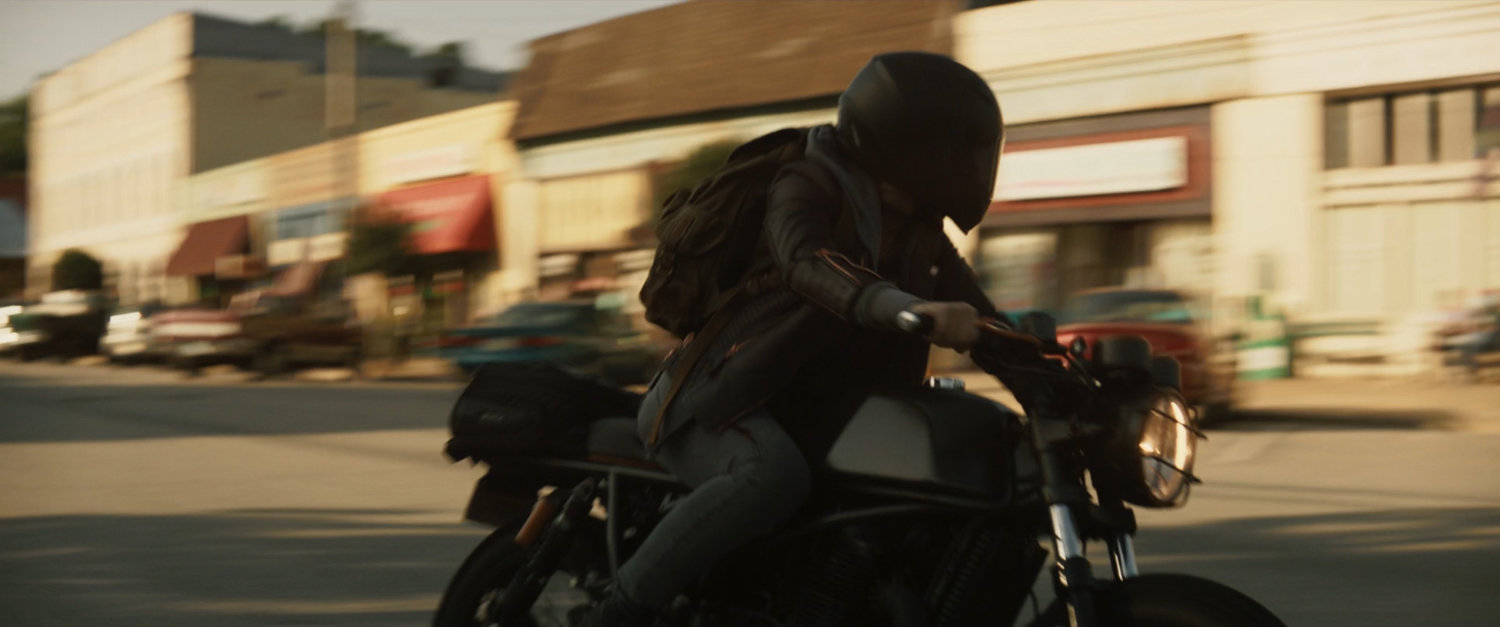 Maya on motorcycle turning corner in downtown Tamaha.