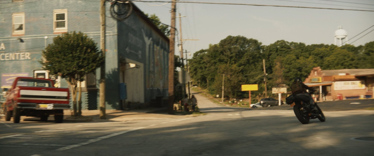 Maya on motorcycle turning corner in downtown Tamaha.