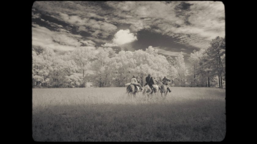 Lighthorsemen riding across field.