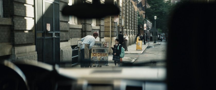 Young Maya signs to ice cream vendor on New York street outside private school.