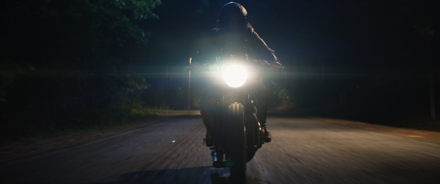 Maya on her motorcycle on a country road at night.