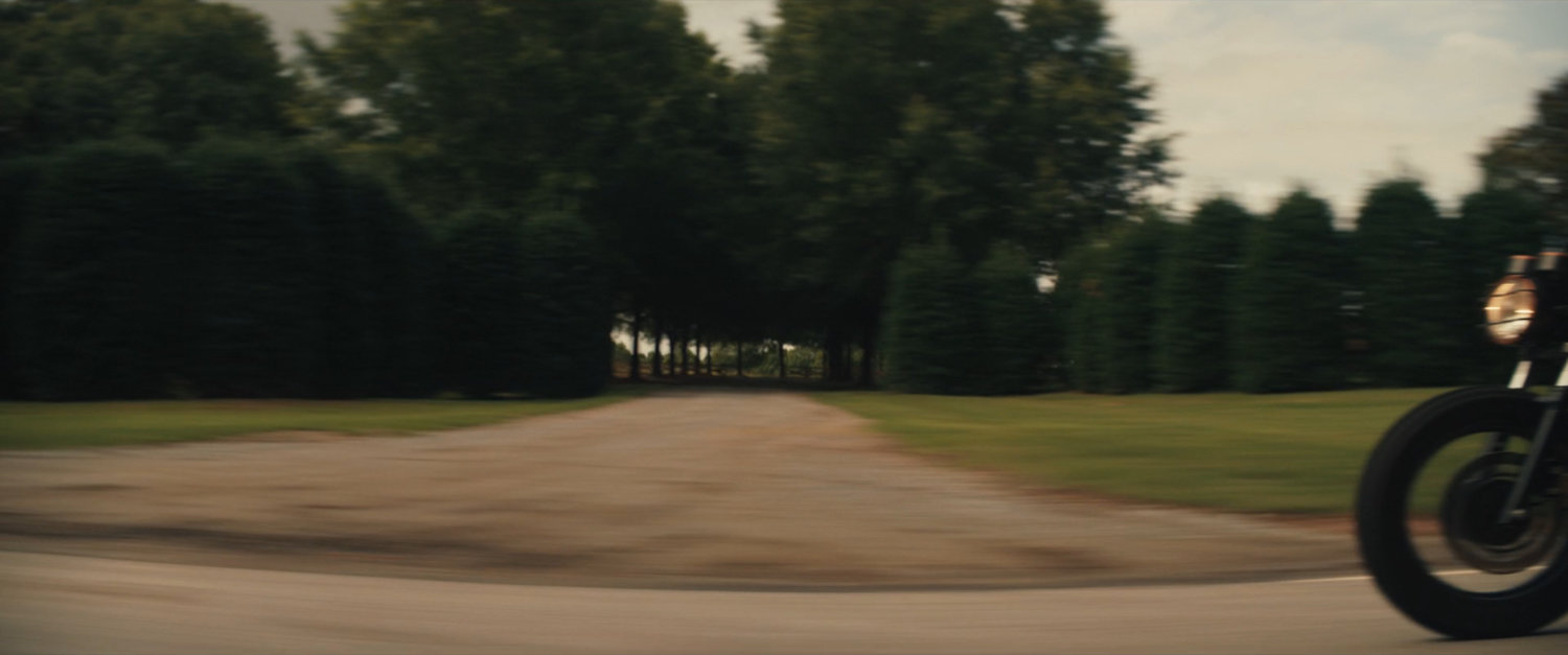 Maya on her motorcycle on a country road.