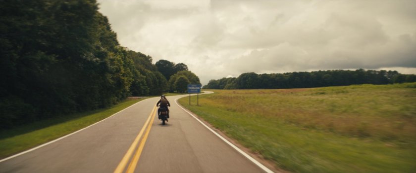 Maya on her motorcycle on a country road.