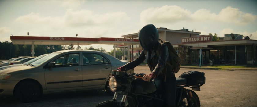 Maya pulling her motorcycle in to Roxxon Travel Store.