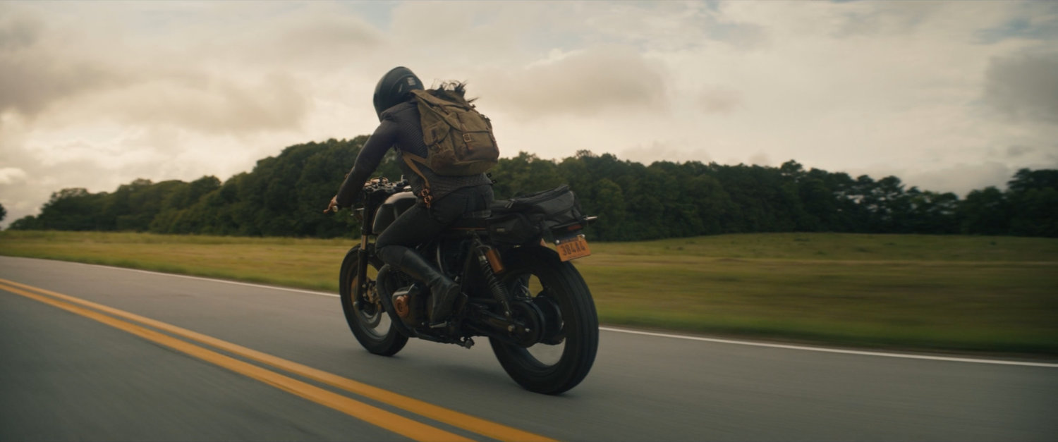 Maya on her motorcycle on a country road.