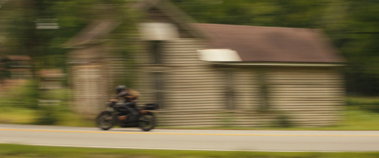 Maya on motorcycle driving out of downtown Tamaha.