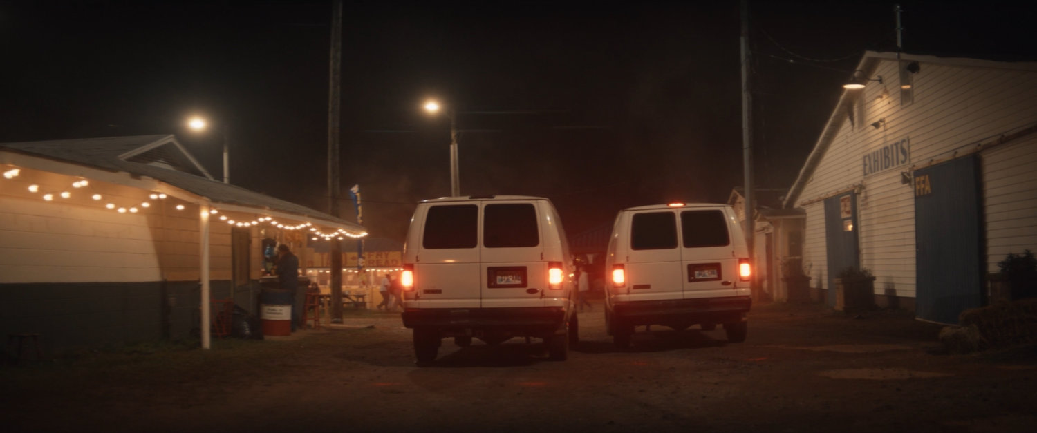Vans pull through the Choctaw Nation PowWow at night.