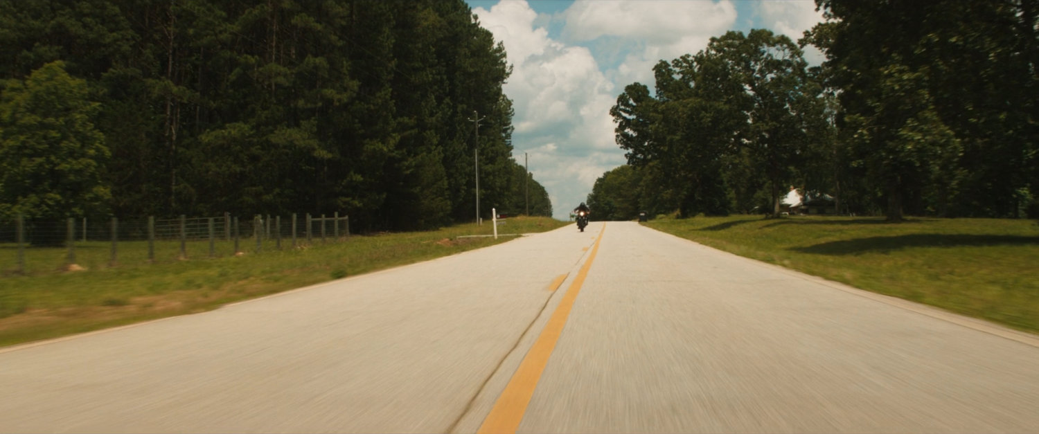 Maya on her motorcycle on a country road.