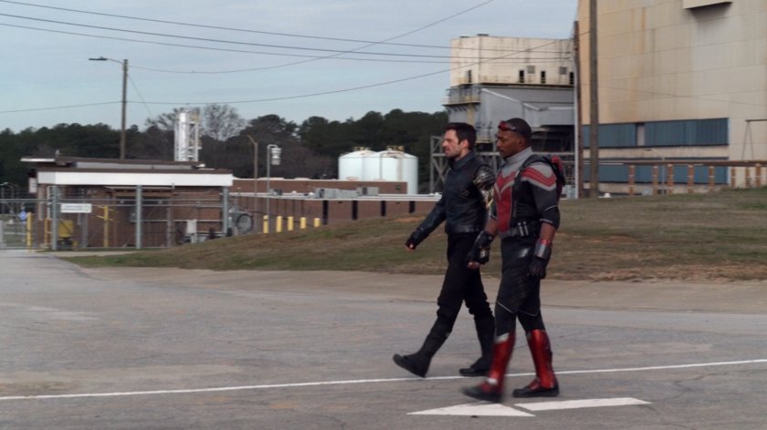 Sam and Bucky walk in front of a factory in a cut scene.
