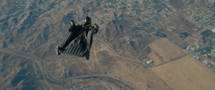 Behind the scenes view of wing suit over desert area.