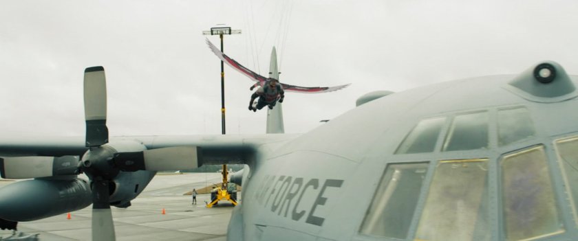 Behind the scenes shot of Falcon, suspended on wires, approaching Air Force plane.