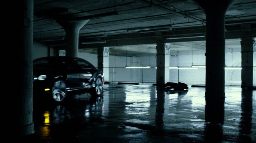 Man laying on ground in stark white parking garage.