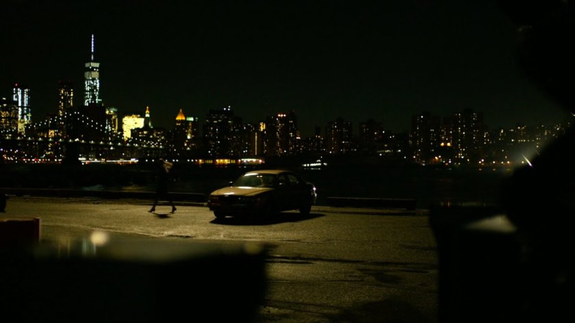 Karen walking away from Ben's car parked on a deserted dock at night.