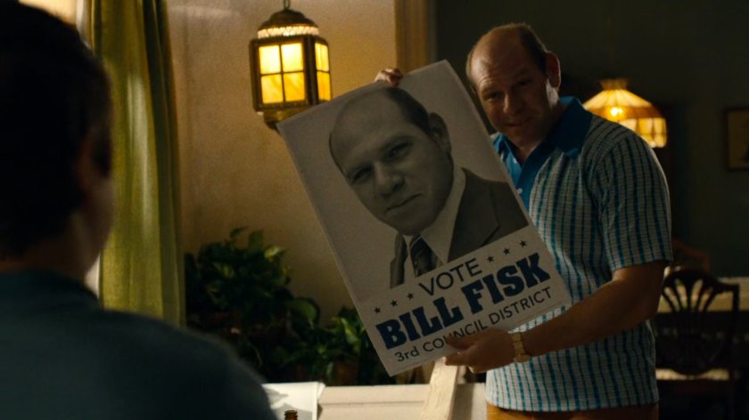 Bill Fisk holding a poster for his campaign inside his apartment.