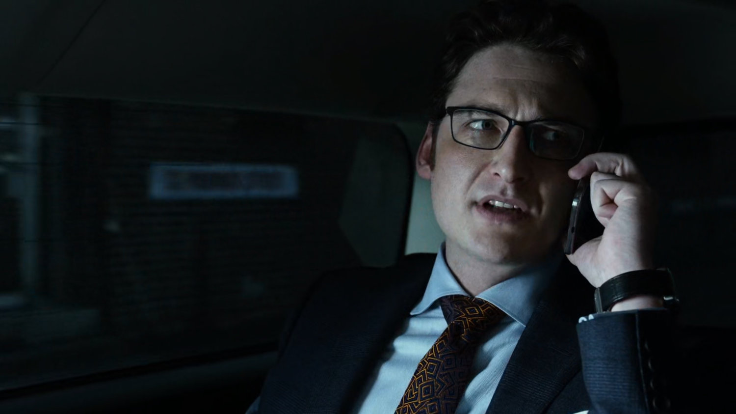 Wesley on phone in back seat of car.