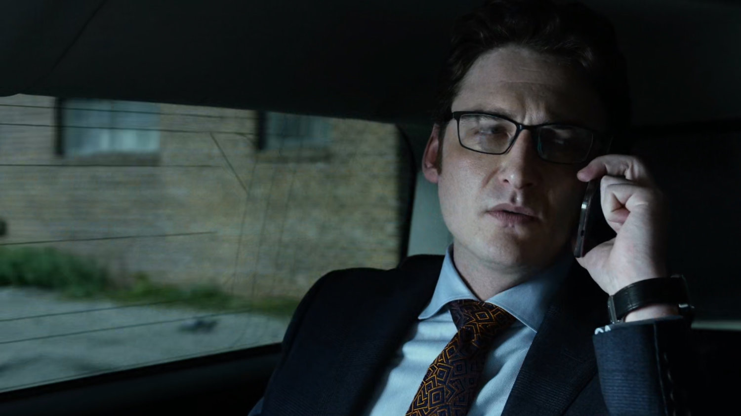 Wesley on phone in back seat of car.