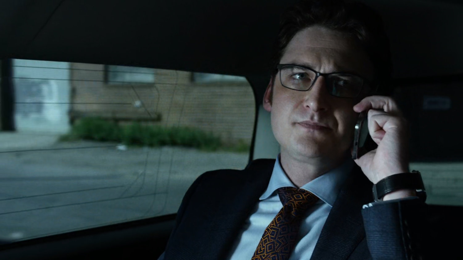 Wesley on phone in back seat of car.
