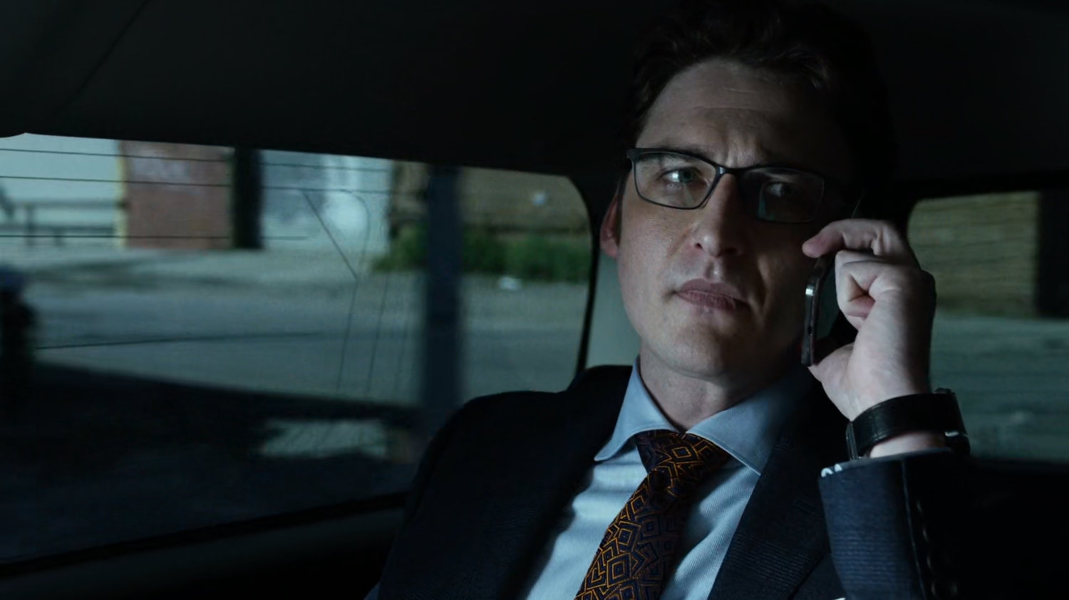 Wesley on phone in back seat of car.