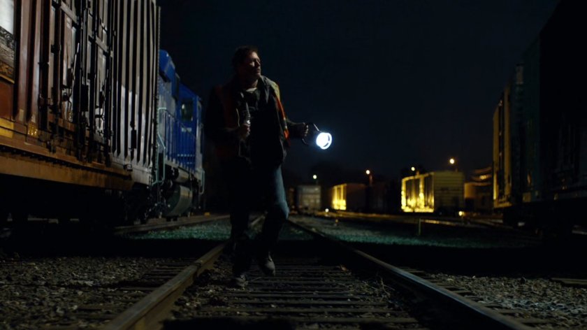 Man walking through railroad yard at night.