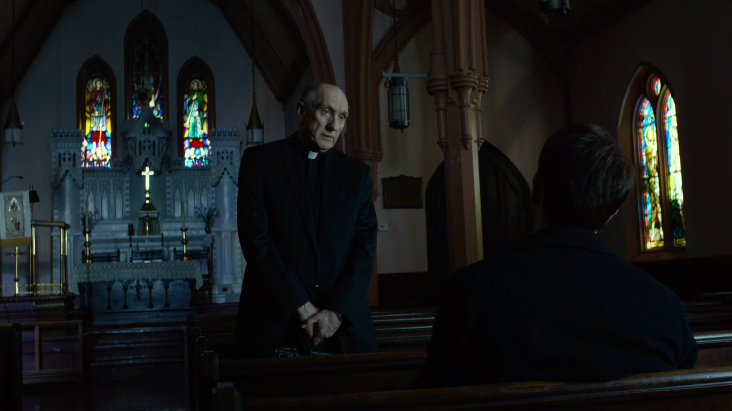 Matt and Father Lantom in church pews.