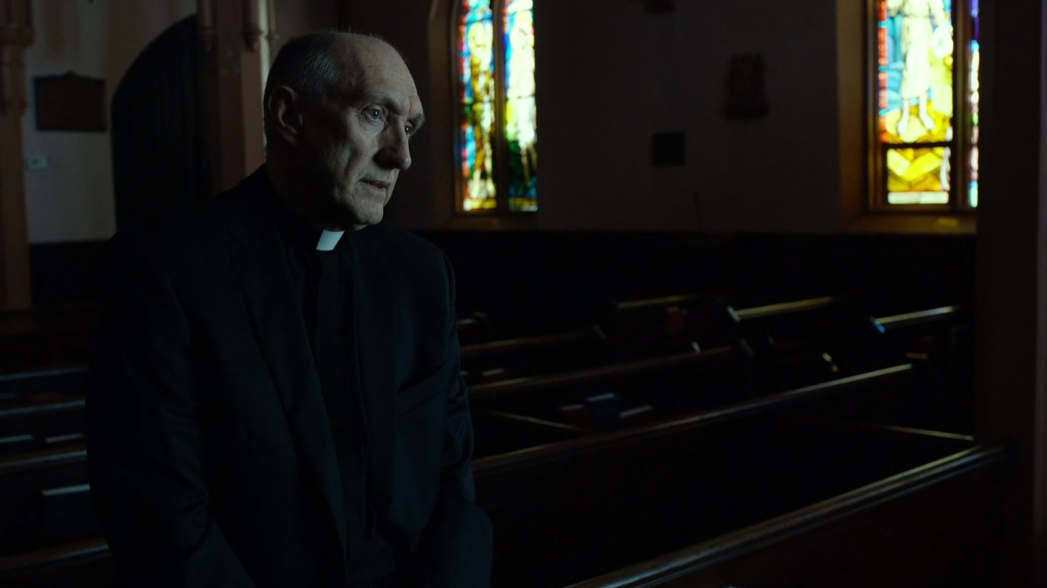 Father Lantom in church pews.