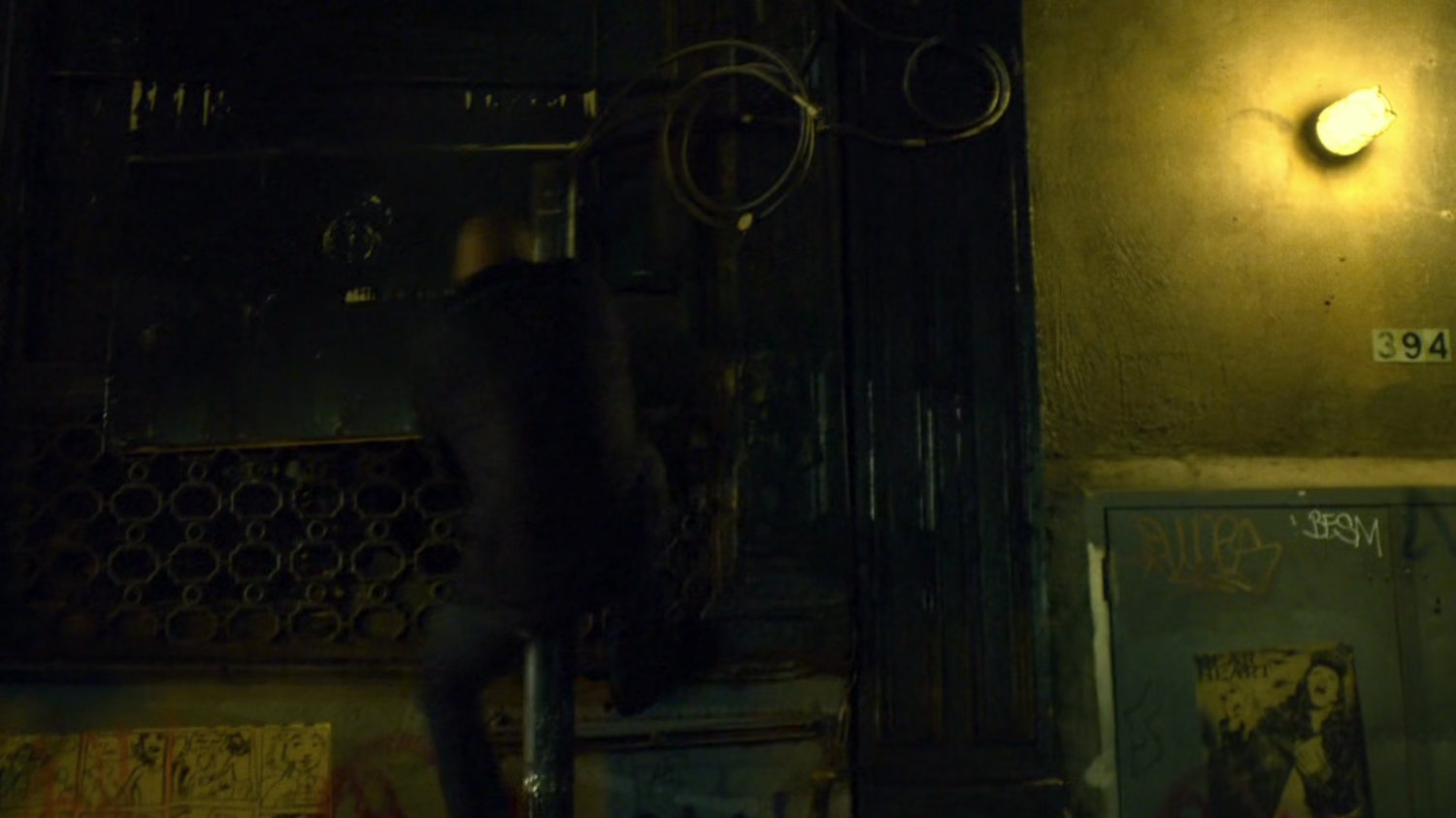 Turk climbing a fire escape in a dark alley.