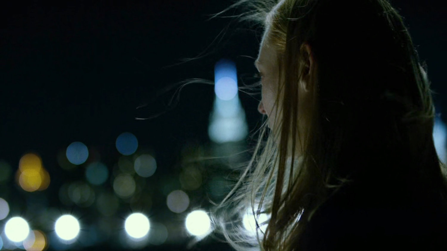 Karen standing at the water's edge at night.