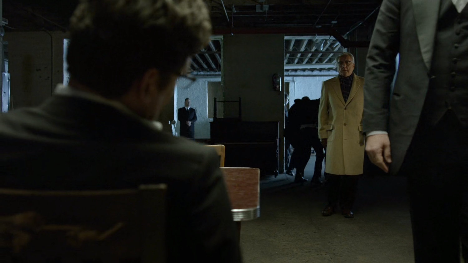 Fisk and Leland with Wesley's body in a dark basement.