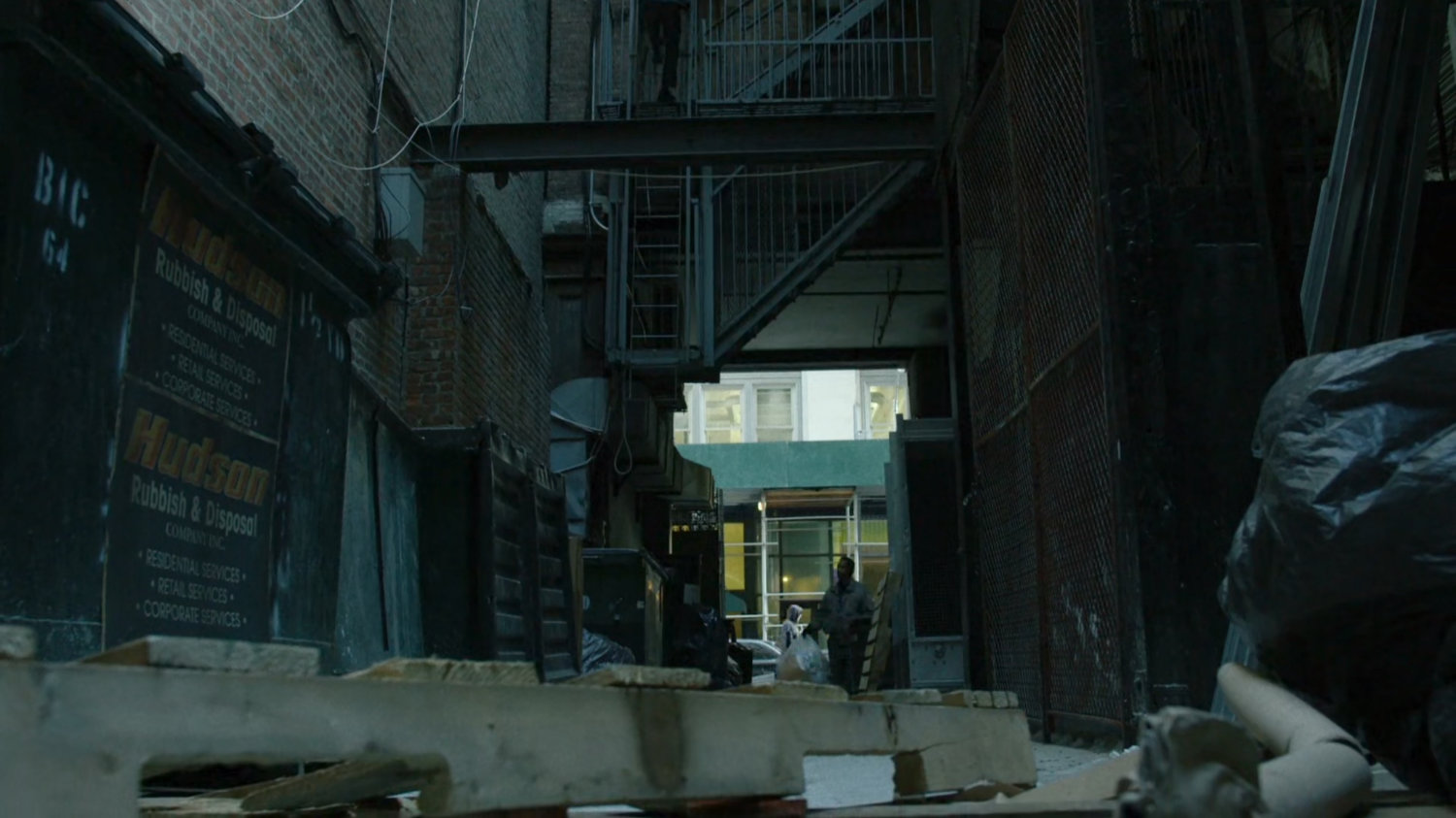 Man walks into alley with bag of trash.