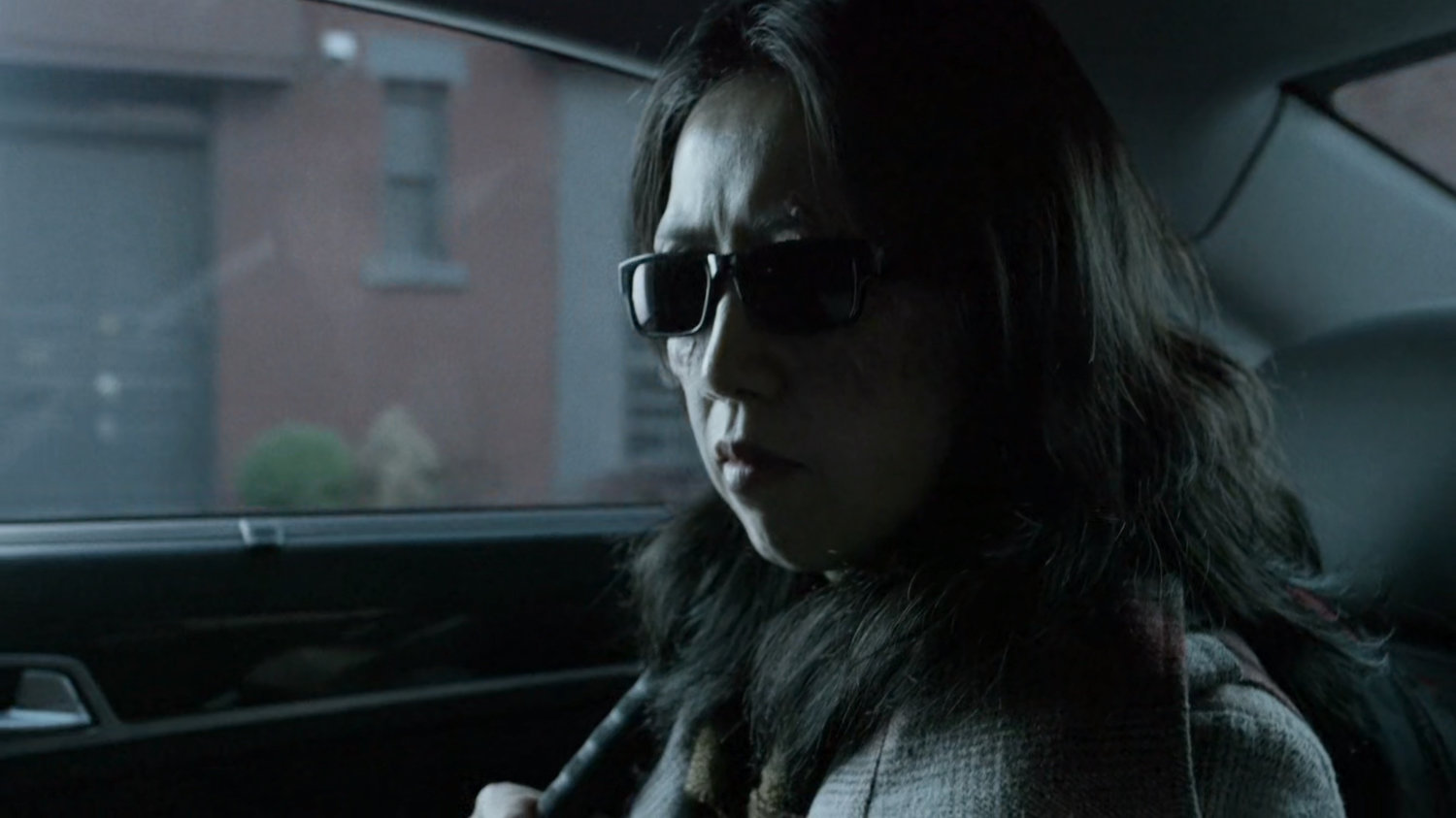 A blind courier in the back seat of a car.