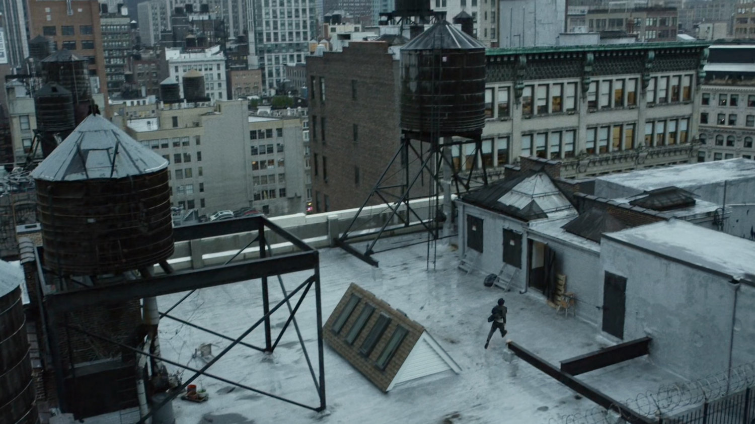 Matt runs across a New York rooftop, by a water towers.