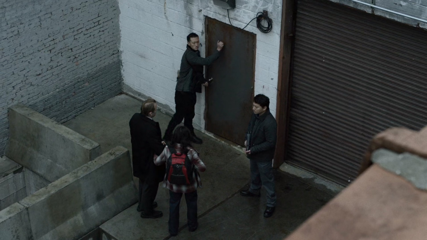 Courier enters back door of warehouse as seen from rooftop.