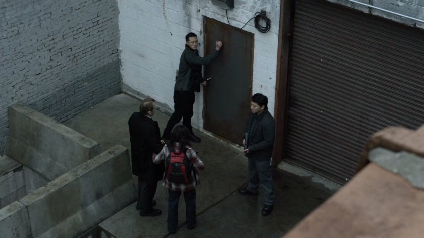 Courier enters back door of warehouse as seen from rooftop.