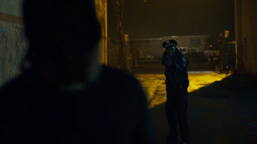 Officer Brett Mahoney draws gun on Man in Black in dark alley.