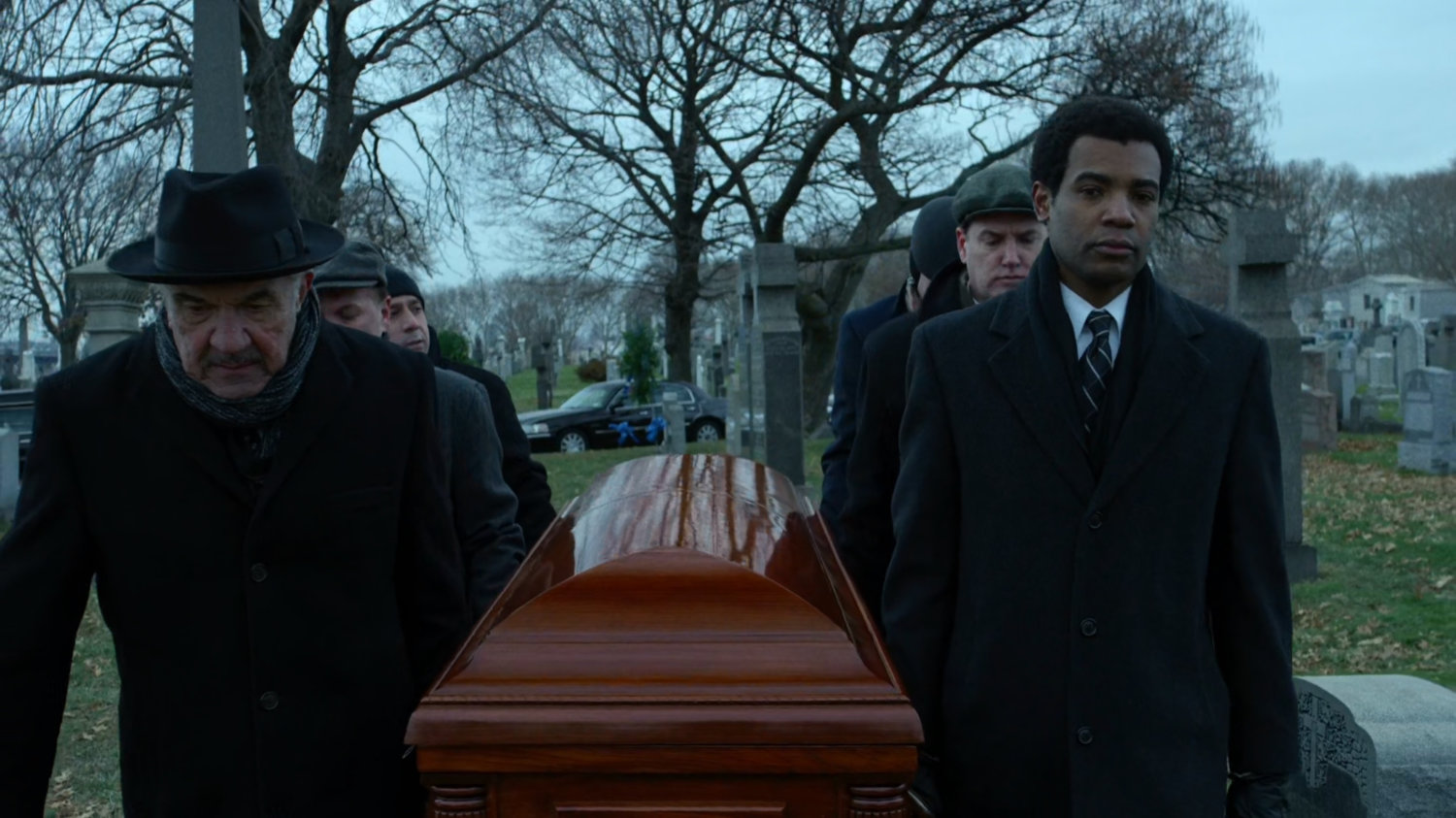 Pallbearers with casket at cemetery.