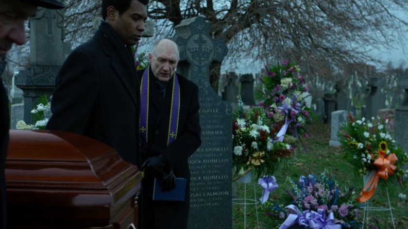 Pallbearers and Father Lantom with casket at cemetery.