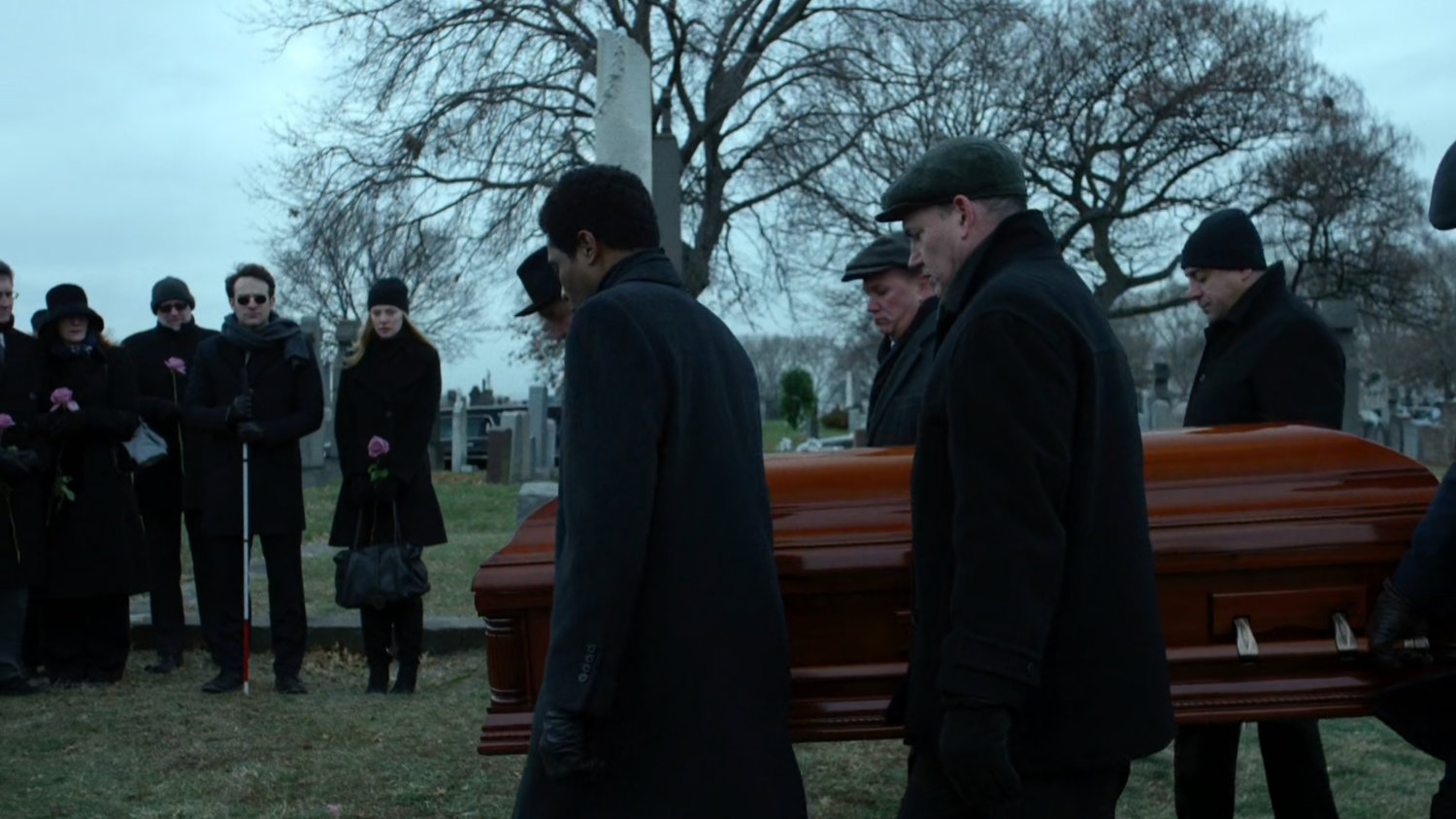 Pallbearers with casket at cemetery.