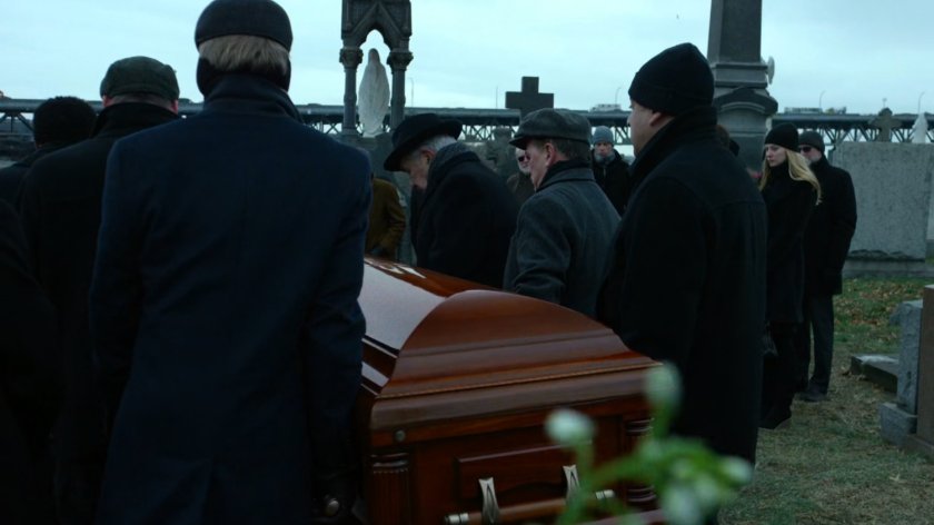 Pallbearers with casket at cemetery.