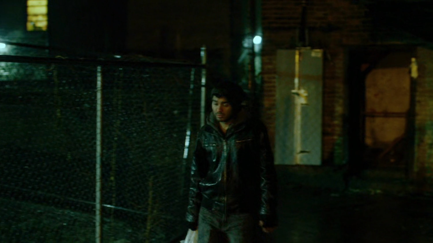 Man in dark alley behind abandoned theater.