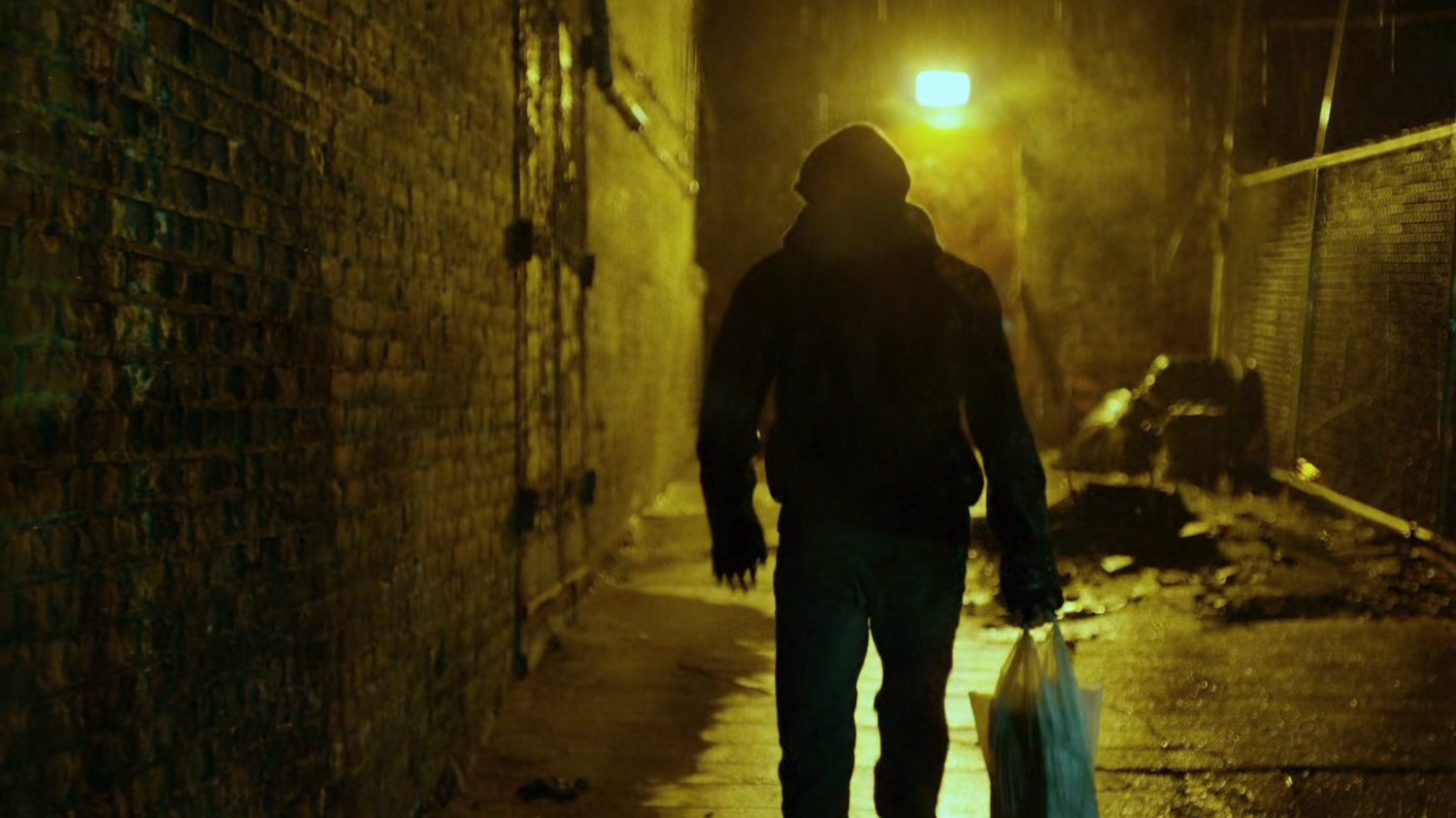 Man in dark alley behind abandoned theater.