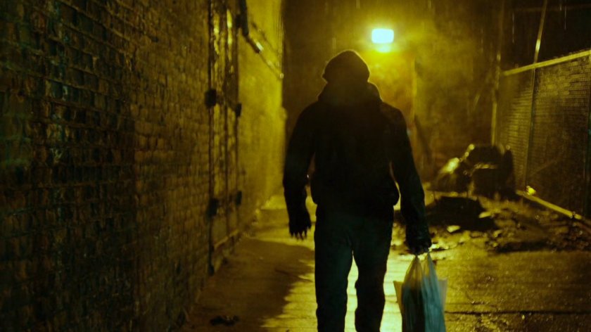 Man in dark alley behind abandoned theater.