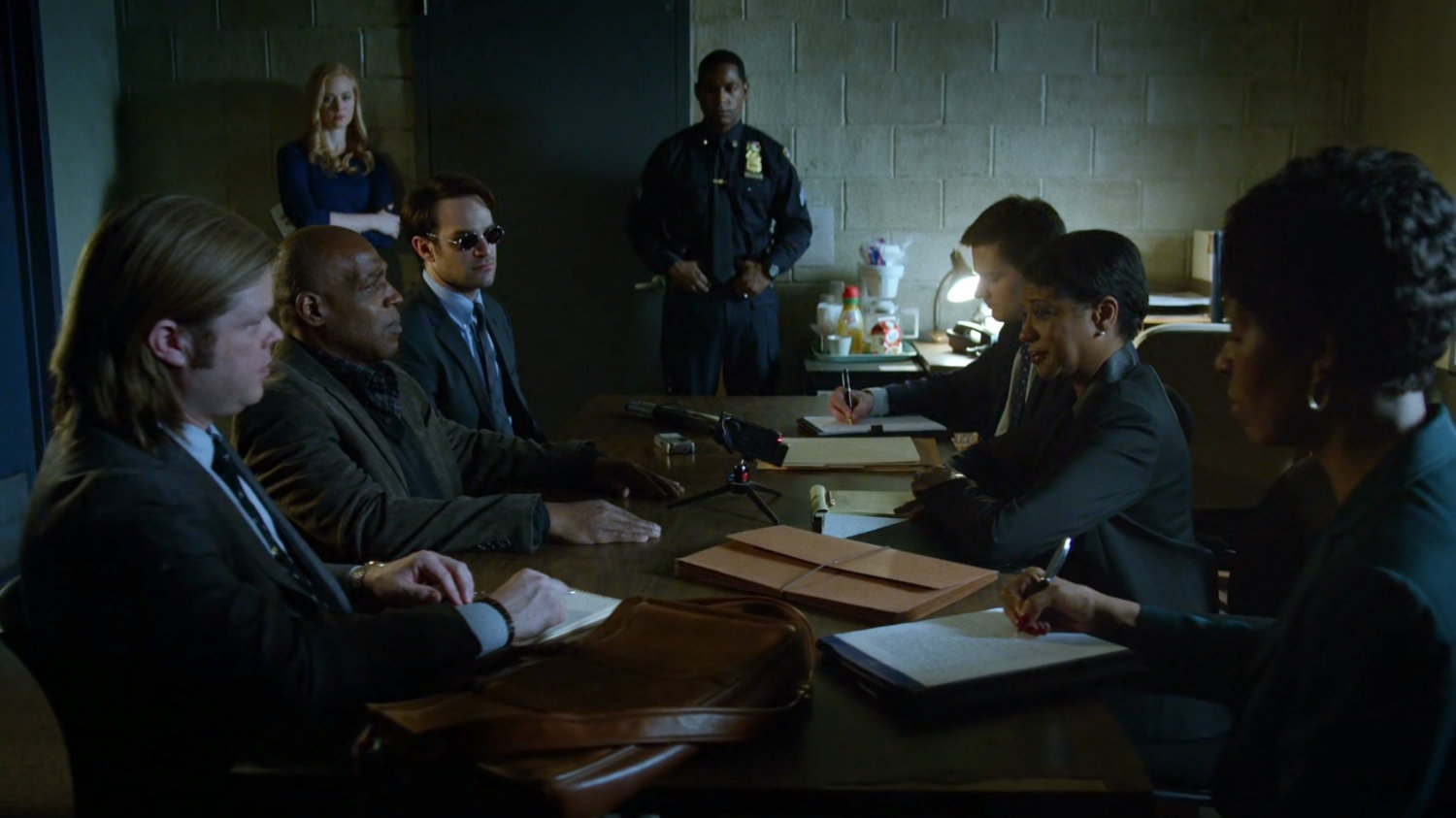 Matt, Foggy, Detective Hoffman, Brett, and police detectives in meeting room.