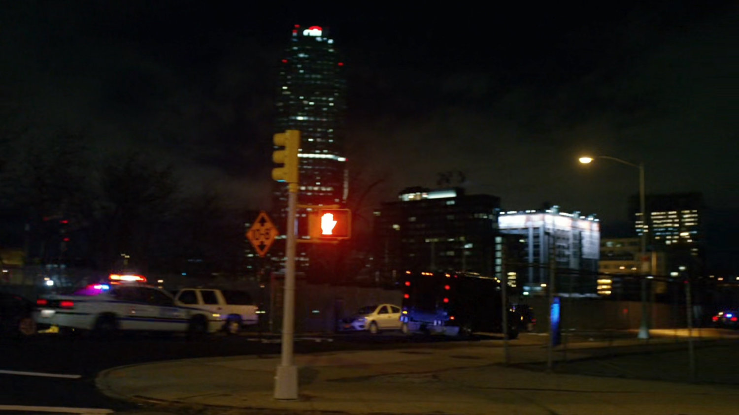 Police cars drive along a city street.