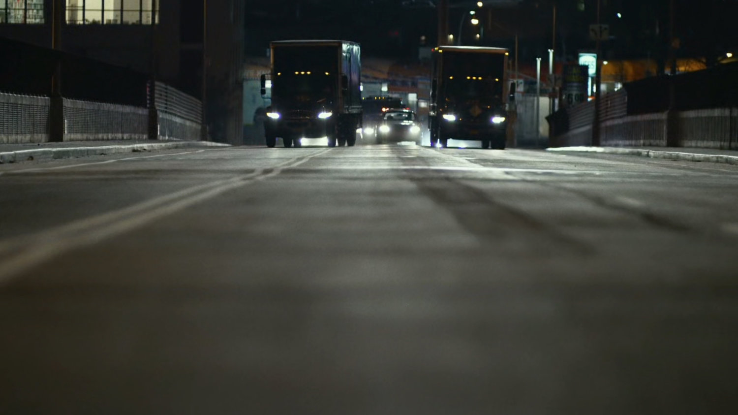 A pair of vans block police cars on a small bridge.