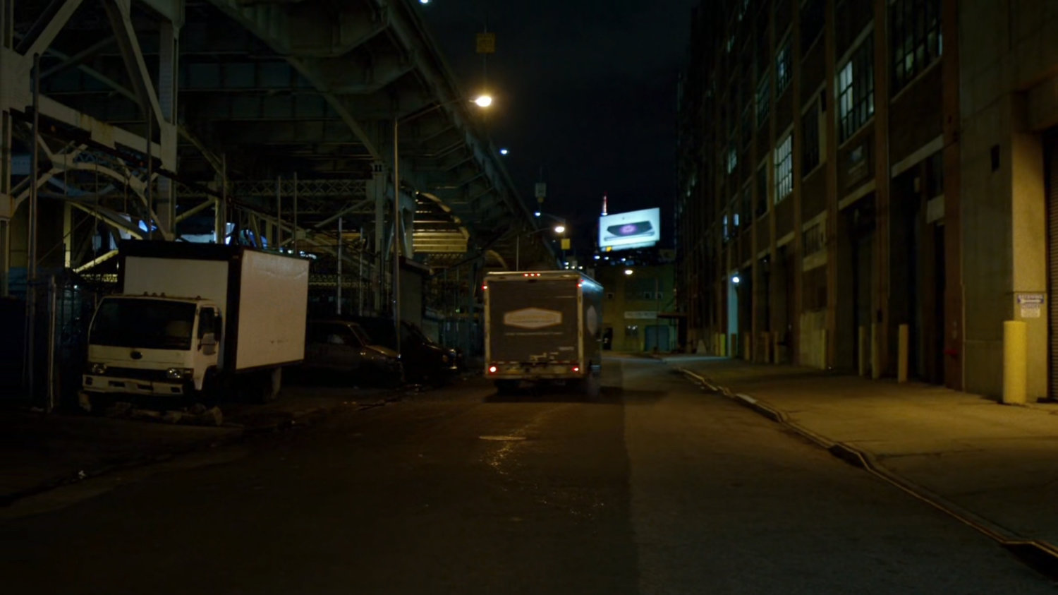 A moving truck driving out of a garage onto the street.