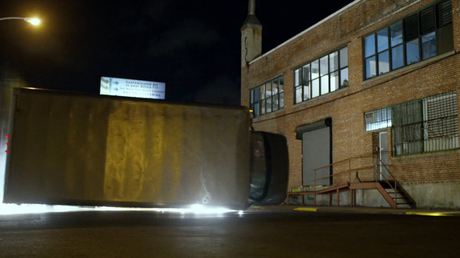 Truck flipping on its side along city street.