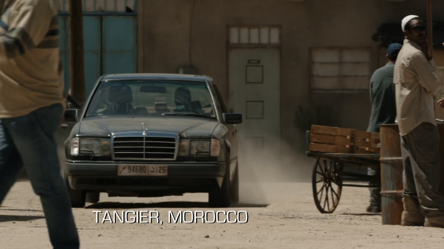 Black sedan on dusty street in Tangier. Text: Tangier, Morocco.