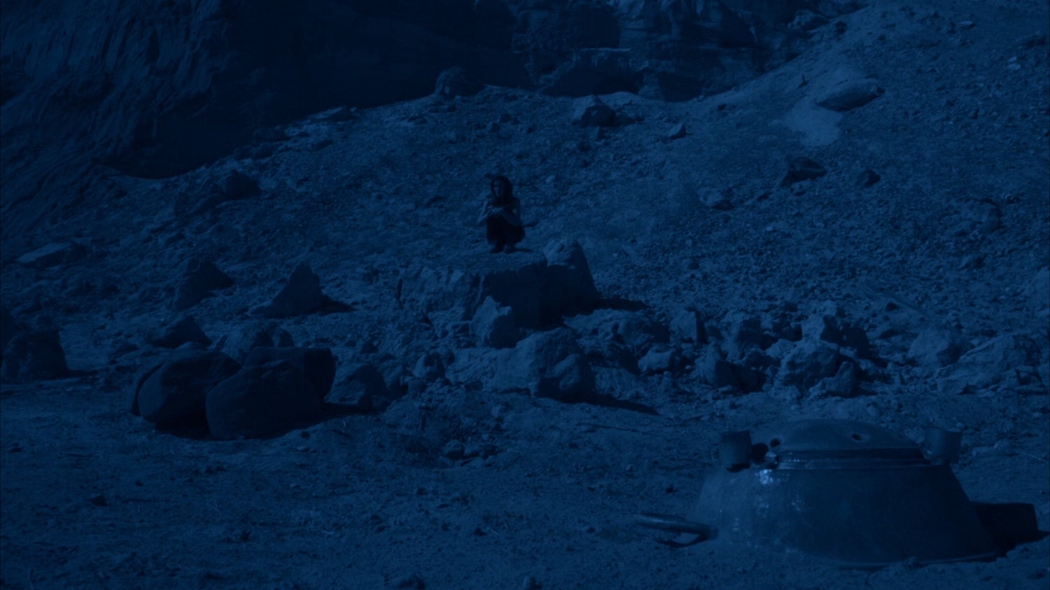 Jemma sits on a rock outside the hatch to the bunker on Maveth.